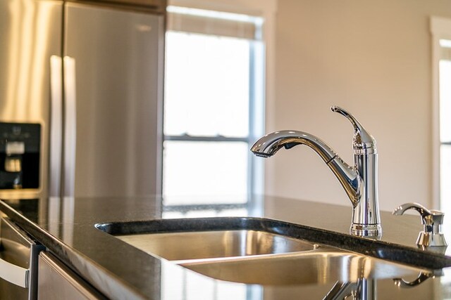 interior details featuring dark countertops, stainless steel refrigerator with ice dispenser, and a sink