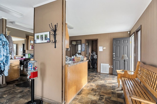 interior space with stone finish flooring, wooden walls, visible vents, and light countertops