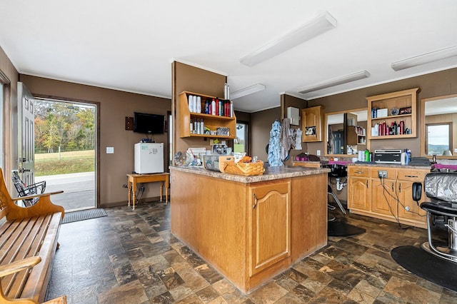 kitchen with light countertops, a toaster, open shelves, and stone finish flooring