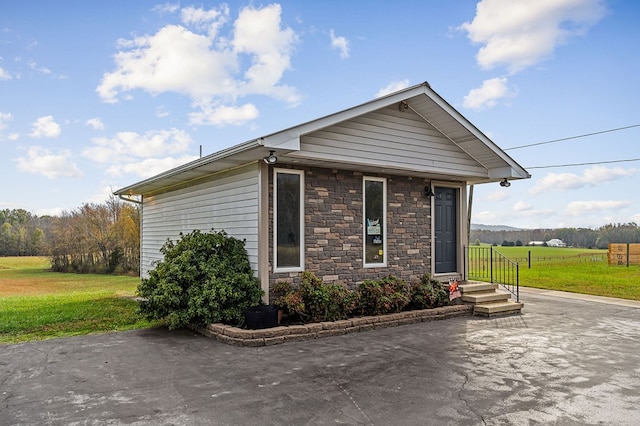 view of property exterior featuring stone siding, a yard, and a patio