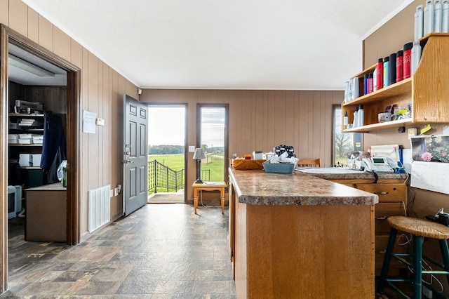 kitchen with stone finish flooring, a breakfast bar, visible vents, open shelves, and dark countertops