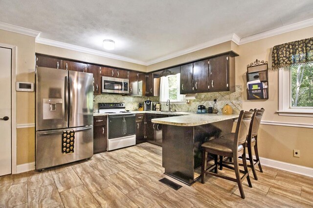 kitchen featuring stainless steel appliances, visible vents, light countertops, dark brown cabinets, and a peninsula