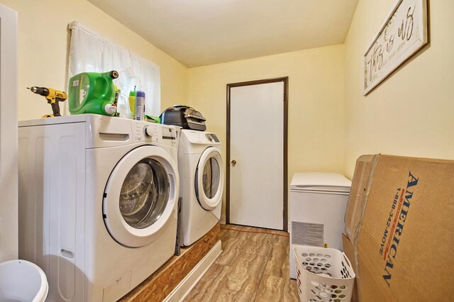 clothes washing area with laundry area, separate washer and dryer, and light wood finished floors