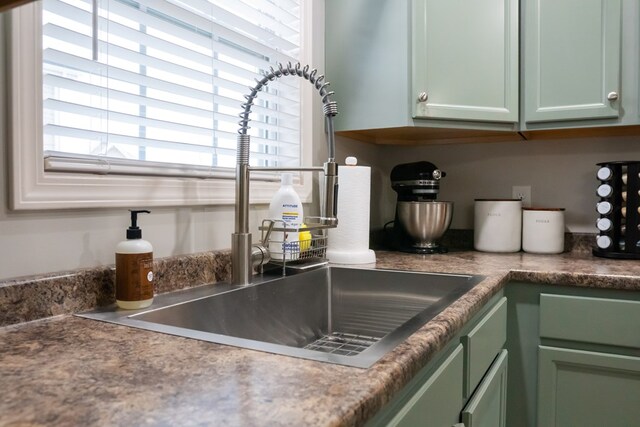 details with dark countertops, green cabinets, and a sink