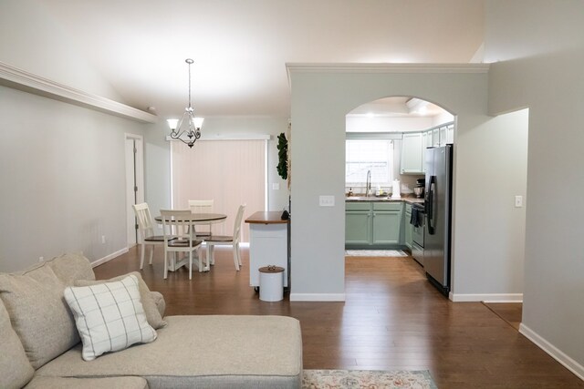 living room with dark wood-style floors, arched walkways, and baseboards