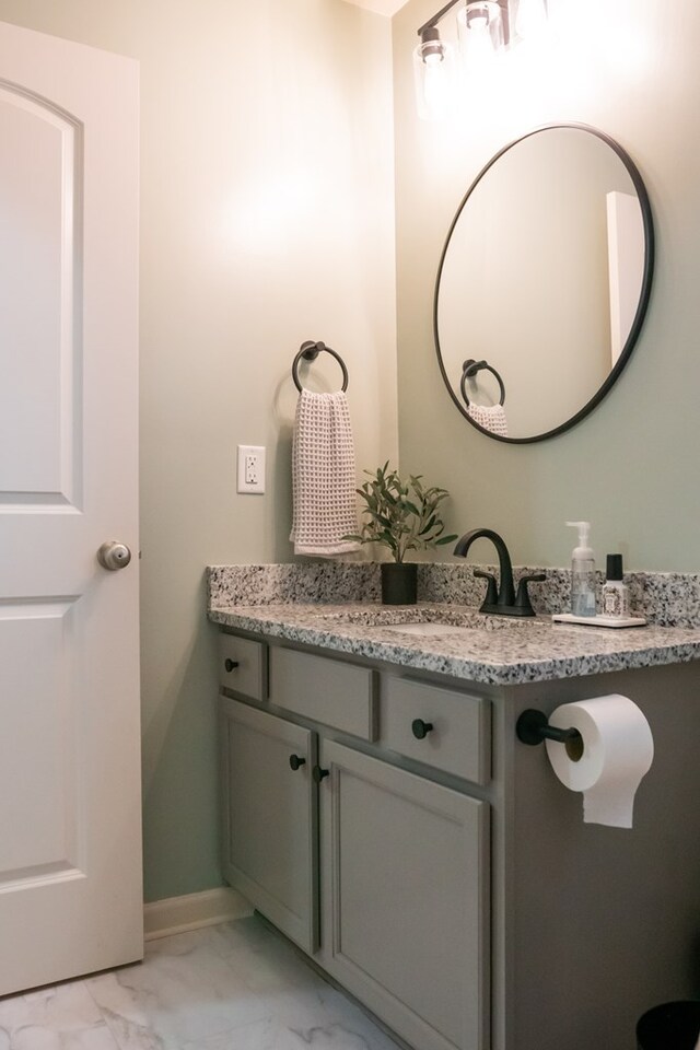 bathroom with marble finish floor, baseboards, and vanity