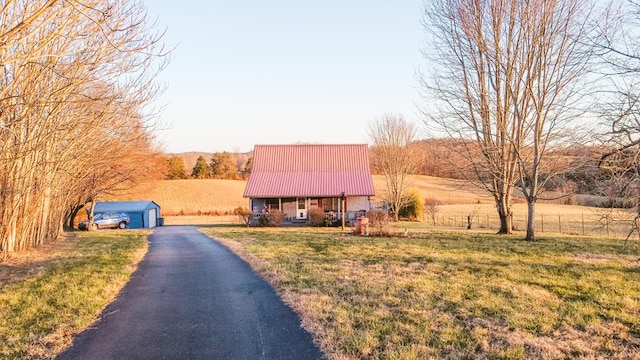 view of front of house featuring an outdoor structure, a rural view, a front lawn, and metal roof