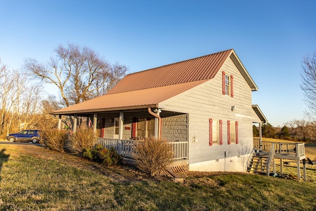 view of home's exterior featuring a porch, a lawn, and metal roof