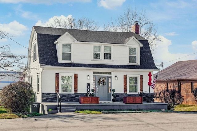 dutch colonial with a chimney, a gambrel roof, and roof with shingles