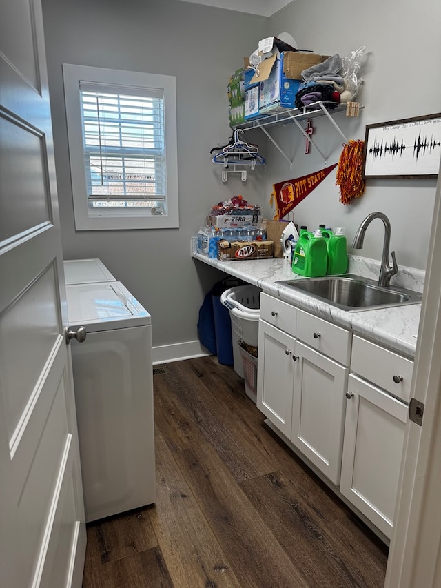 clothes washing area featuring dark wood-style flooring, a sink, baseboards, cabinet space, and washing machine and clothes dryer