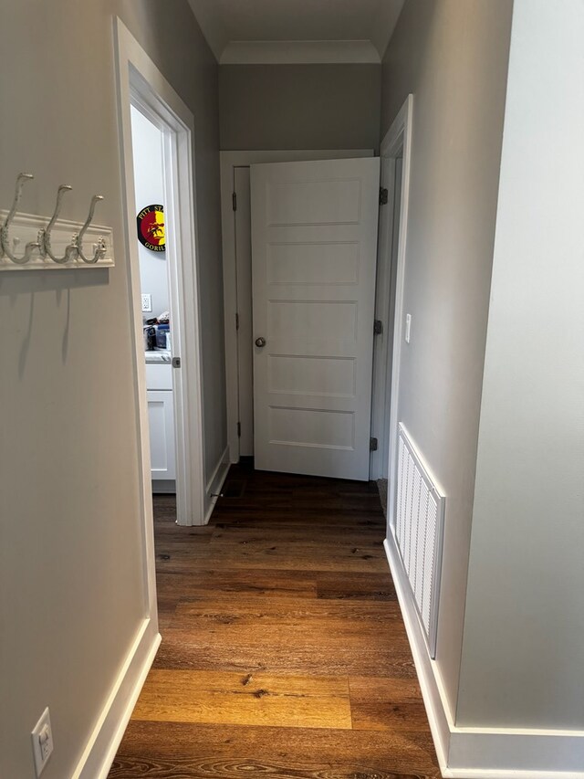 hall featuring visible vents, dark wood-style flooring, and ornamental molding