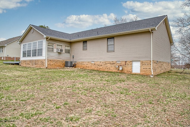 rear view of house featuring cooling unit and a lawn