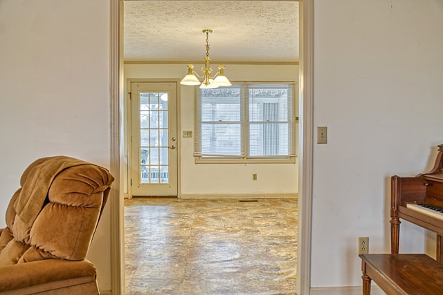 doorway with a chandelier, a textured ceiling, and baseboards