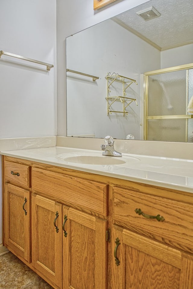 bathroom featuring a textured ceiling, vanity, visible vents, and a shower stall