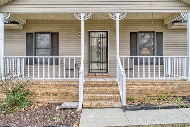 property entrance with covered porch and brick siding