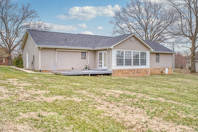 back of property featuring roof with shingles, a lawn, brick siding, and a wooden deck