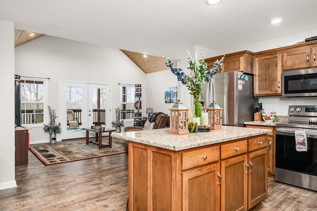 kitchen featuring appliances with stainless steel finishes, dark wood-style flooring, brown cabinetry, and a kitchen island