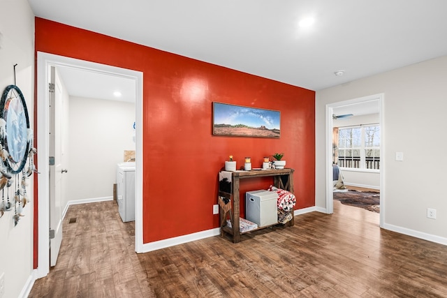 hall featuring dark wood-style flooring, washing machine and dryer, and baseboards