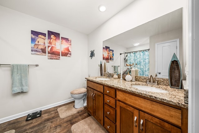 full bathroom featuring double vanity, wood finished floors, a sink, and baseboards