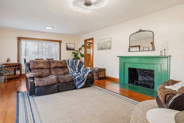 living area featuring ornamental molding, a brick fireplace, baseboards, and wood finished floors