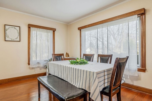 dining area featuring crown molding, baseboards, and wood finished floors