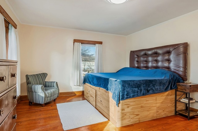 bedroom with ornamental molding and wood finished floors