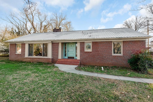 single story home with metal roof, a chimney, a front lawn, and brick siding