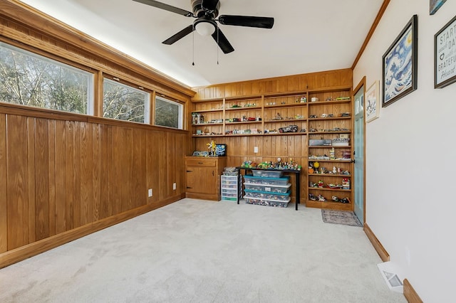 interior space with visible vents, light colored carpet, ceiling fan, and wooden walls