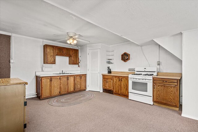 kitchen with light carpet, a sink, light countertops, brown cabinets, and white gas range