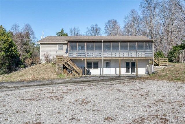 back of property featuring stairs and a sunroom