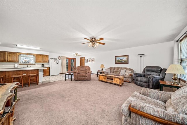 living room with light colored carpet, ceiling fan, and a textured ceiling