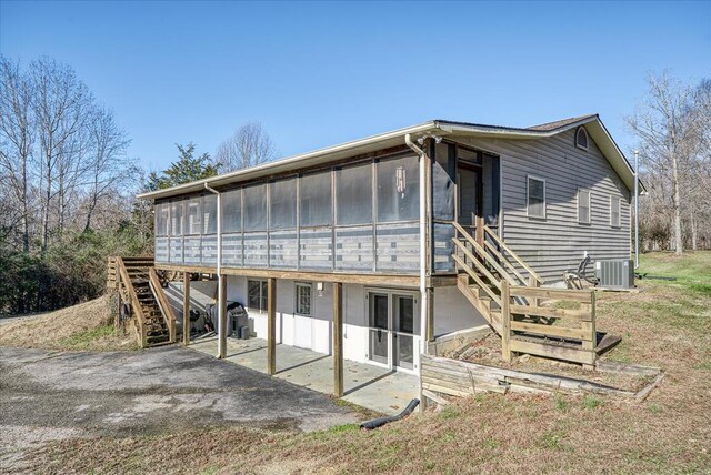 rear view of house with central AC unit, aphalt driveway, a sunroom, stairway, and a patio area