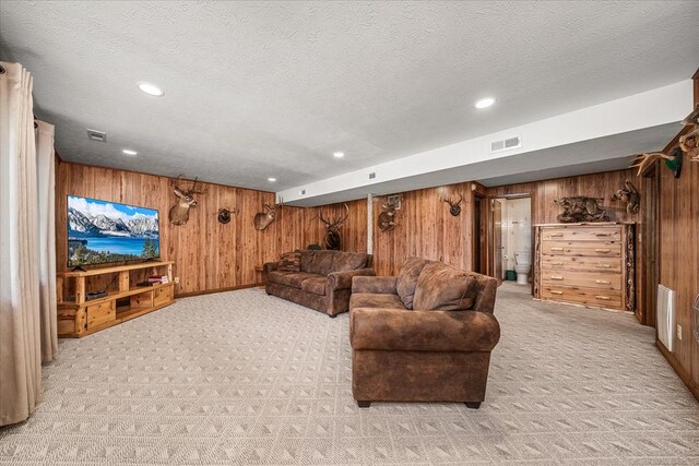 living area featuring a textured ceiling, recessed lighting, light carpet, wood walls, and visible vents