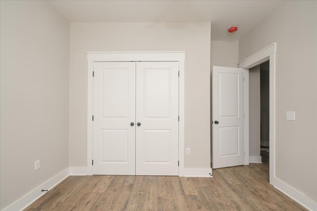 unfurnished bedroom with a closet, baseboards, and wood finished floors