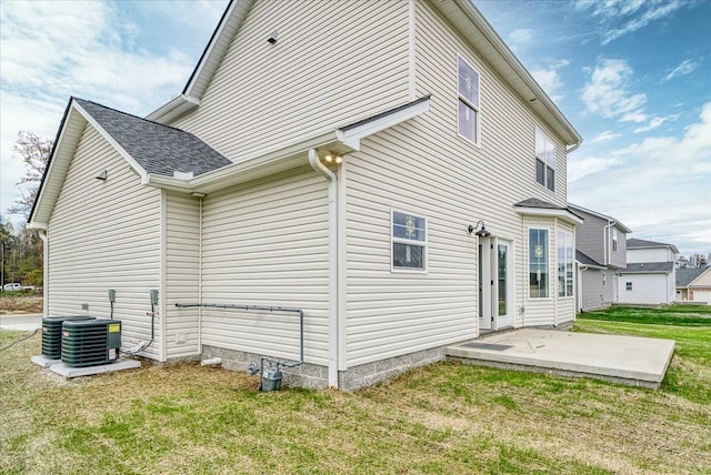 view of side of home featuring a patio, central AC unit, a lawn, and a shingled roof