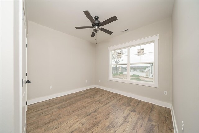 empty room featuring visible vents, ceiling fan, baseboards, and wood finished floors