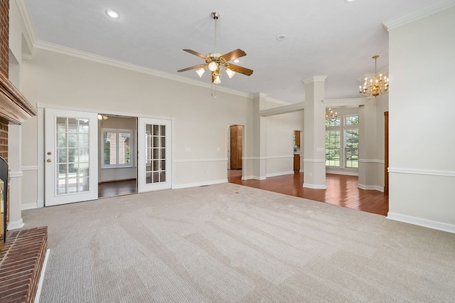 unfurnished living room featuring a fireplace, dark carpet, crown molding, and ceiling fan with notable chandelier