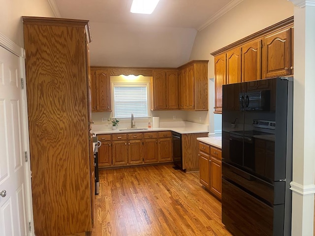 kitchen with brown cabinets, black appliances, light countertops, and a sink