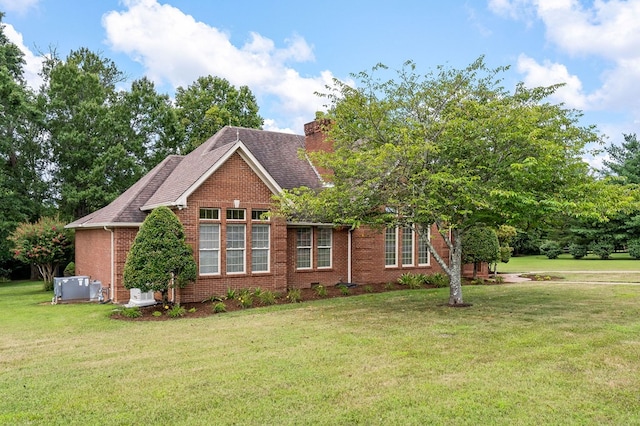 view of side of property featuring central air condition unit, brick siding, roof with shingles, a lawn, and a chimney