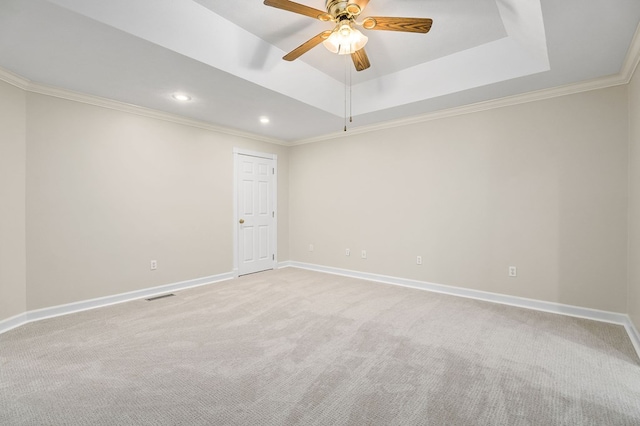 empty room featuring crown molding, a tray ceiling, visible vents, and baseboards