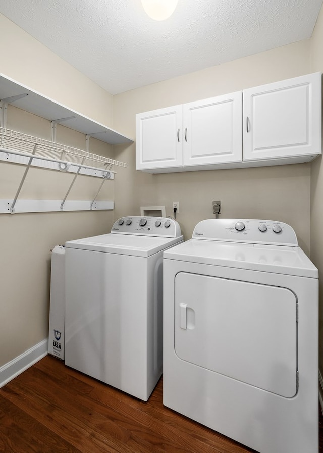 laundry room featuring cabinet space, baseboards, dark wood-style floors, a textured ceiling, and separate washer and dryer