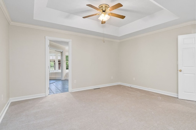 empty room with light carpet, a raised ceiling, visible vents, and baseboards