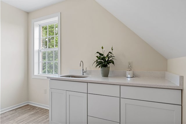 bathroom with lofted ceiling, wood finished floors, vanity, and baseboards