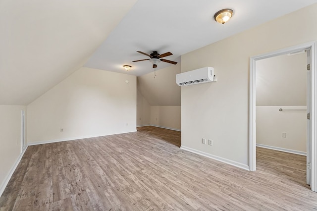 additional living space with baseboards, ceiling fan, light wood-style flooring, a wall mounted air conditioner, and vaulted ceiling