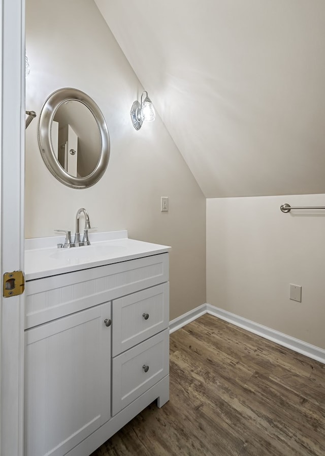 bathroom featuring vaulted ceiling, vanity, baseboards, and wood finished floors