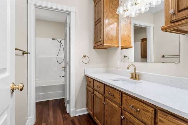 bathroom featuring shower / washtub combination, vanity, baseboards, and wood finished floors