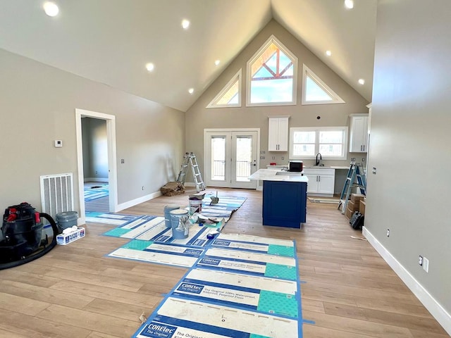 living area with high vaulted ceiling, visible vents, baseboards, french doors, and light wood-type flooring