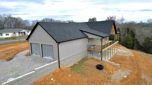 view of front of property featuring a shingled roof, a wooden deck, and a garage