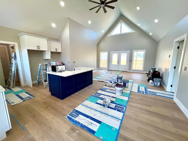 kitchen featuring light wood-style floors, white cabinets, light countertops, french doors, and an island with sink