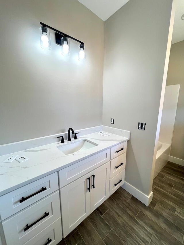 full bathroom featuring wood finish floors, vanity, and baseboards